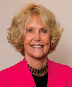 Head shot of Sheryl wearing a dark pink jacket