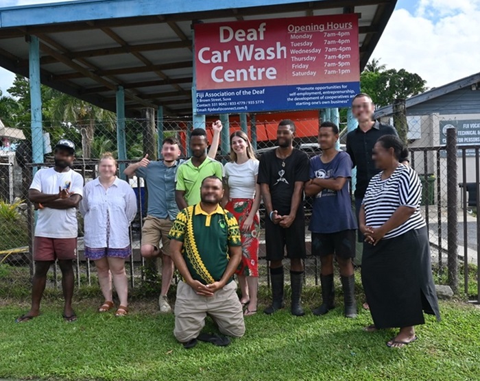 Brielle standing with a group of people in front of the Deaf Car Wash Centre