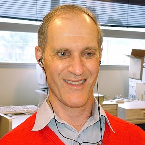 Headshot of Andrew Downie wearing a red jumper