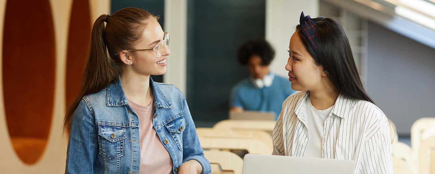 Picture of two people in a classroom situation talking.