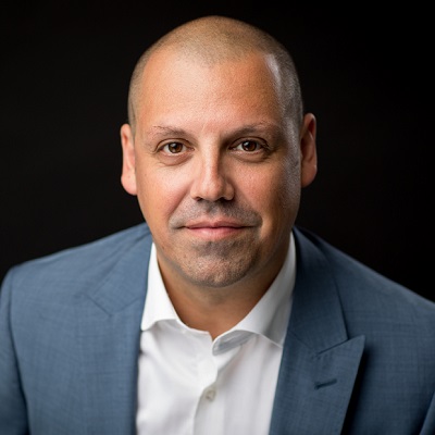 Head shot of Daniel Valiente-Riedl wearing a grey suit jacket with white shirt