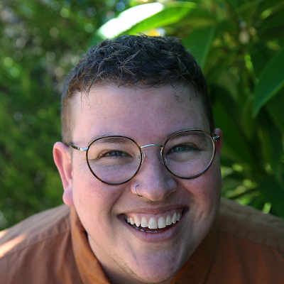 Headshot of Stevie Lane, standing in front of plants and smiling