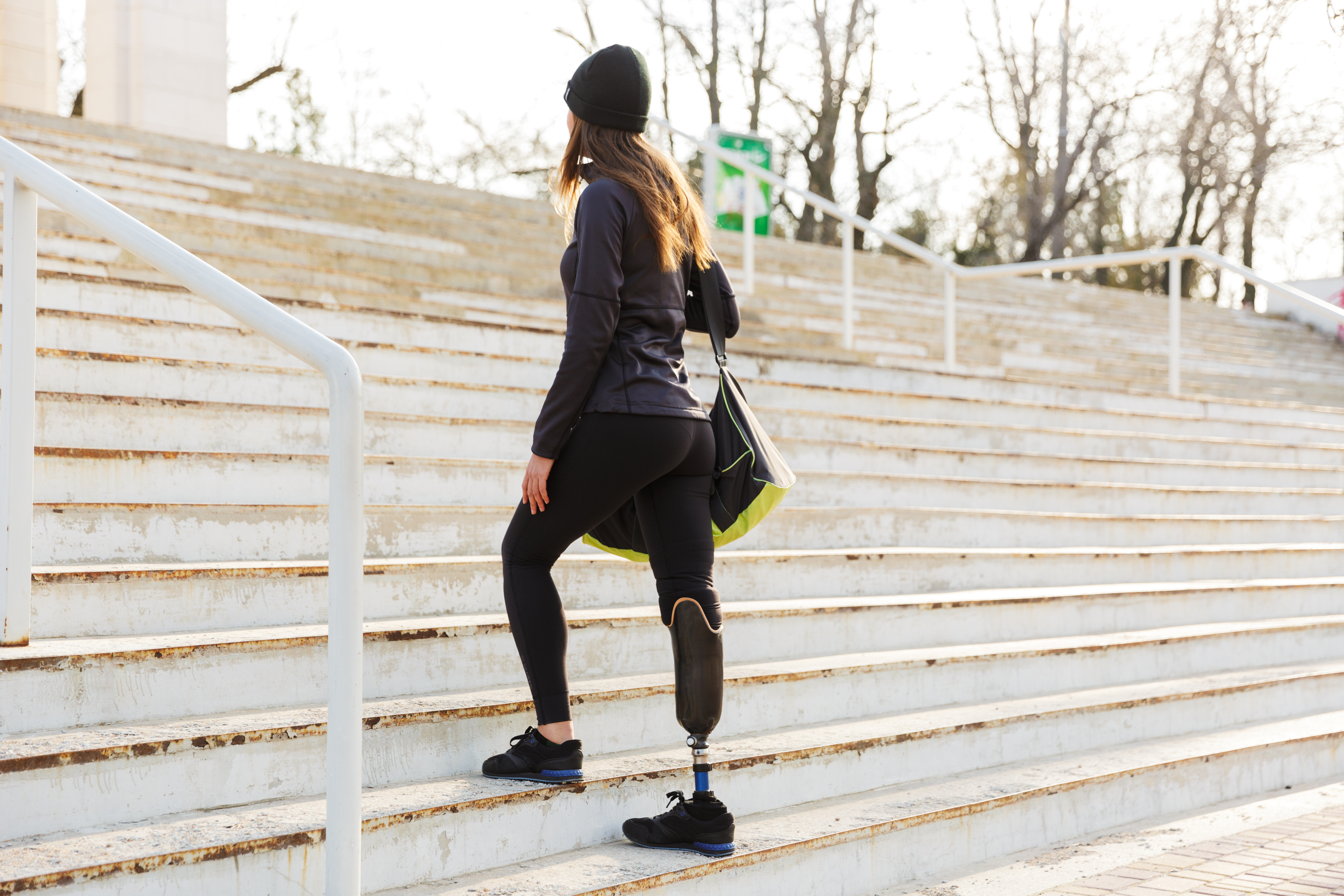 A student with a prosthetic limb walking up stairs