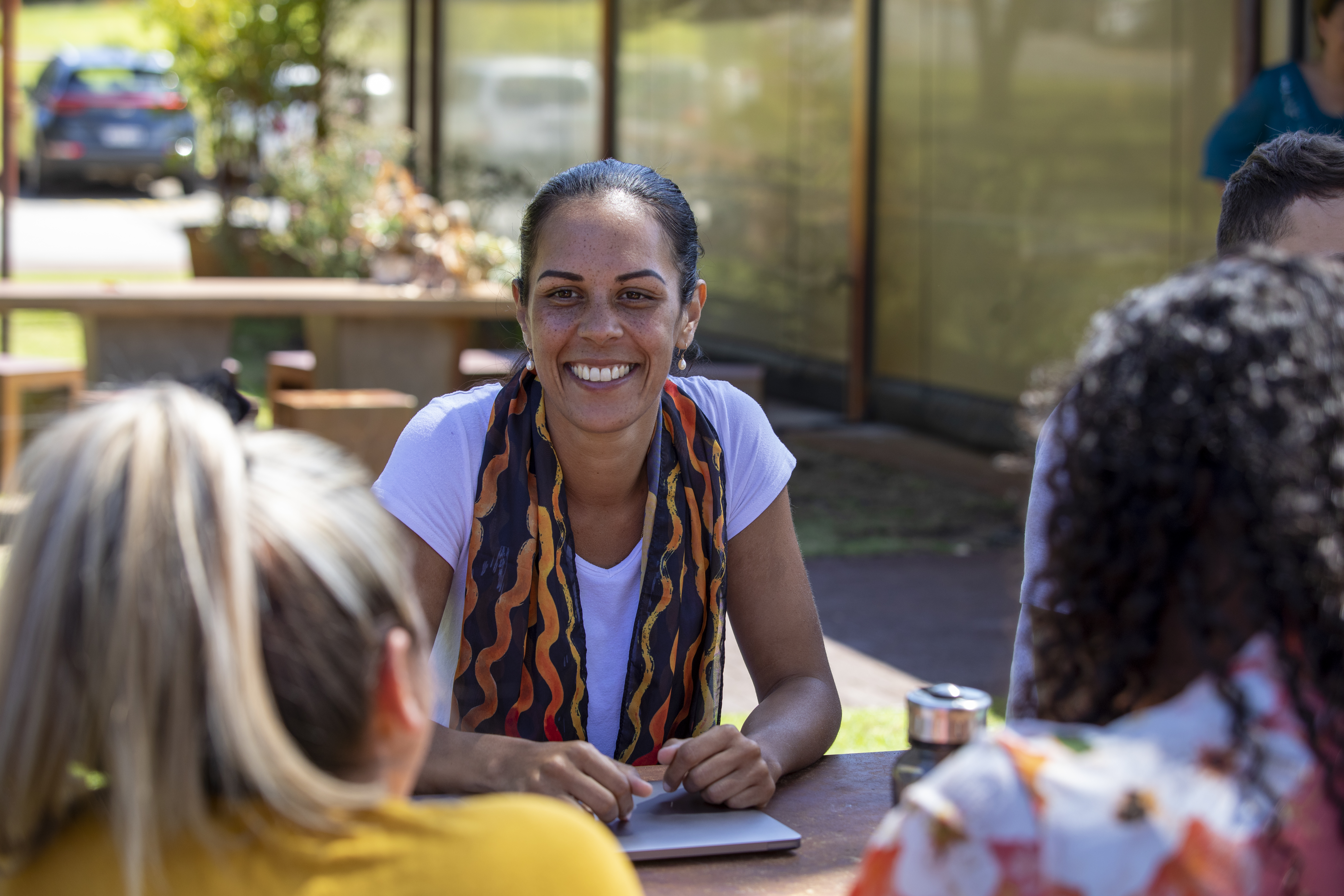 An Aboriginal woman talking with peers at a table.